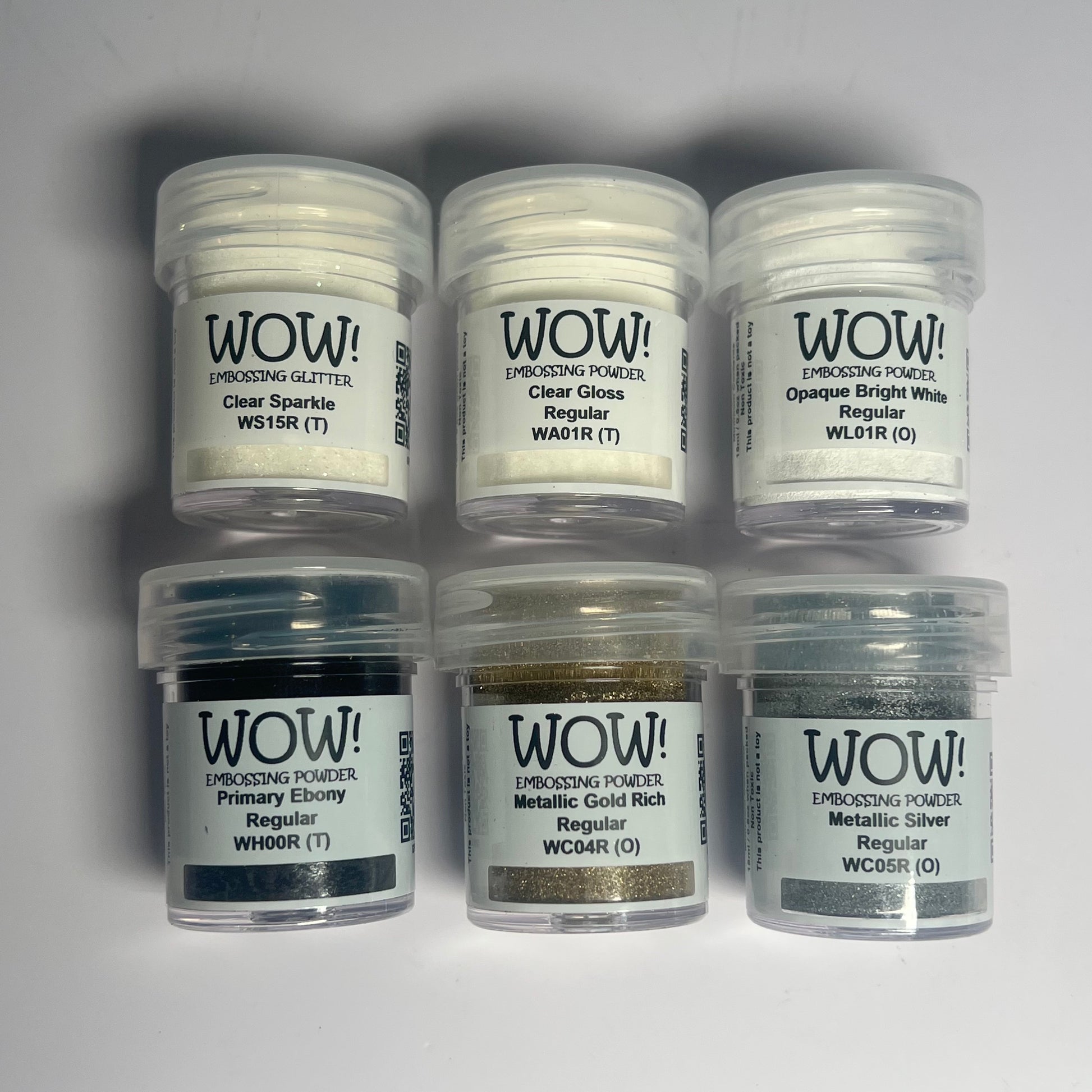 Six jars of WOW! Embossing Powder on a gray background